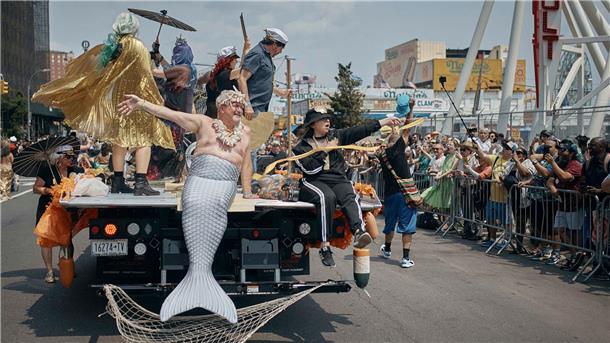 Feiernde grüßen von einem Festwagen.