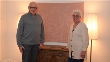 Ferdinand und Ilona Rogge aus Zeven daheim an einer Grafik mit Häusern der Andacht der Bahá'i, die es weltweit gibt. Eines davon steht in Langenhain bei Frankfurt am Main.
