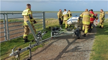 Feuerwehrleute und DLRG-Helfer mit einem Schlauchboot am Langwarder Groden