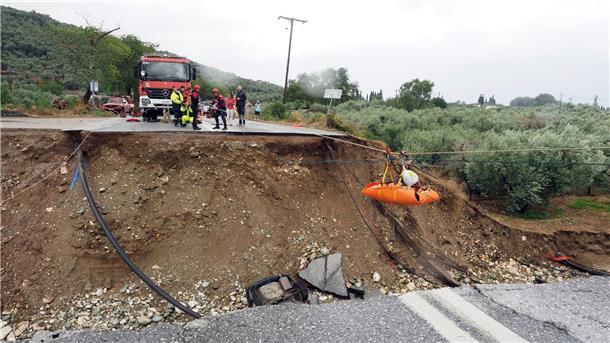 Lage in Griechenland spitzt sich zu Feuerwehrleute heben im griechischen Kala Nera einen Nierenpatienten über eine durch einen Regensturm beschädigte Straße.