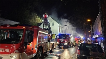 Feuerwehrleute löschen von einer Drehleiter aus.