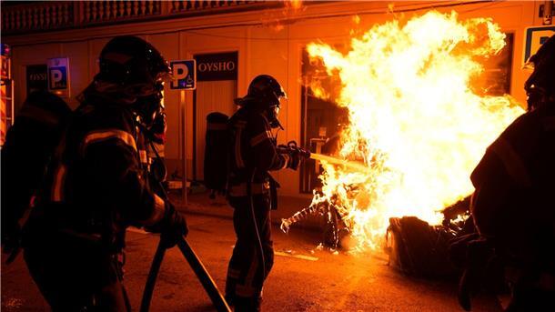 Spanien: Gewalttätige Proteste nach Wiederwahl von Sánchez Feuerwehrleute müssen einen von Demonstranten angezündeten Müllcontainer löschen.