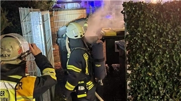 Feuerwehrleute rücken zum brennenden Müllcontainer vor.