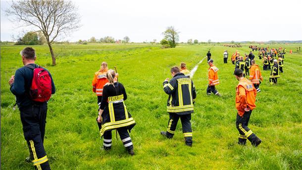 Vermisstenfall Arian: Die Polizei stellt erneute Suche ein Feuerwehrleute suchen mit einer Menschenkette auf einem Feld nach dem vermissten sechs Jahre alte Arian aus Elm.