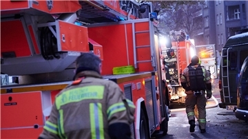 Feuerwehrmänner laufen auf der Schudomerstraße in Berlin-Neukölln zu den Einsatzfahrzeugen.