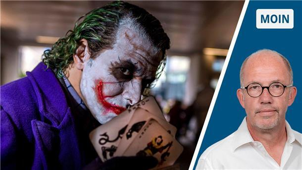 Der Joker aus „Batman" hält Spielkarten in der Hand. 