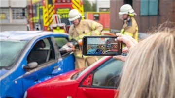 Eine Gafferin filmt Rettungskräfte beim Einsatz am Unfallort. Nachgestellte Szene. 