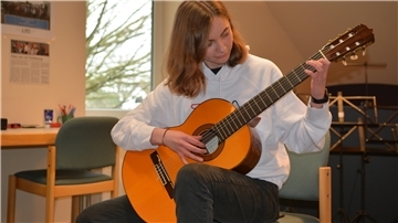 Ein Mädchen mit Gitarre in der Hand.