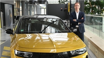Florian Huettl, Geschäftsführer der Opel Automobile GmbH, posiert in der Unternehmenszentrale neben einem Opel Astra.