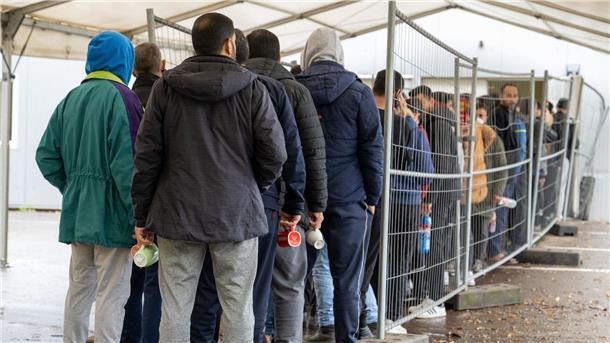 Landkreise kritisieren Flüchtlingspolitik aus Berlin  Flüchtlinge warten in einer Landeserstaufnahmestelle in einer Schlange. Der Landkreistag spricht sich für die Prüfung von Asylanträgen an den EU-Außengrenzen und die Beendigung freiwilliger Aufnahmeprogramme aus.