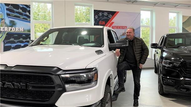 Ein Mann steht neben einem weißen DODGE RAM
