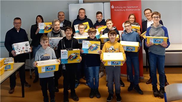 Freude über neue Baukästen: Mehrere Firmen und Gruppen beteiligten sich an einer Spendenaktion für die KGS Tarmstedt. (Von links) Matthias Gerdes (Autohaus Warncke), Sandra Pohl (Schulleiterin), Dr. Monika Rothweiler (Bürgerstiftung Wilstedt), Stefan Heibel (Volksbank Zeven), Chris-Marcel Grotheer (Rewe Markt Tarmstedt), Anne Witt (Lego-Robotik AG), Stefan Kalt (Sparkassen Stiftung) spwie Kinder der Robotik AG