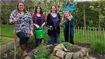 vier Frauen stehen in einem Garten