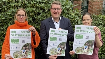 Zwei Frauen und ein Mann halten Werbeblätter für die "Offene Gartenpforte" in ihren Händen.