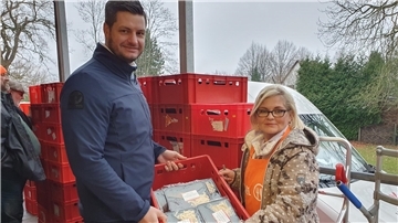 Ein Mann und eine Frau halten eine Kiste mit eingeschweißten Essen.