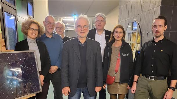 Zwei Frauen und fünf Männer stehen in einem Flur und gucken in Richtung Kamera.