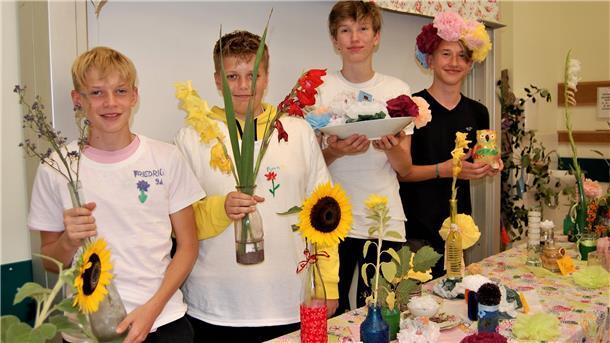 Vier Schüler präsentieren ihre Ergebnisse aus der Blumenwerkstatt.