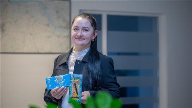 Eine Frau zeigt eine Tafel Schokolade und Souvenirs aus Kasachstan.