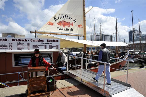 Ein kleines Schiff mit Segel am liegt am Neuen Hafen in Bremerhaven. Auf dem Segel steht Klibfisch, Backfisch.