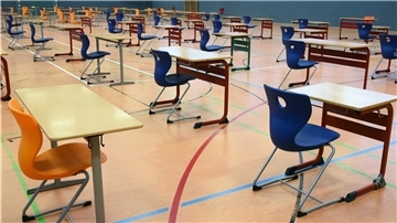 Mit großen Abständen stehen Tische und Stühle in der Turnhalle vom Montessori-Schulzentrum in Leipzig.