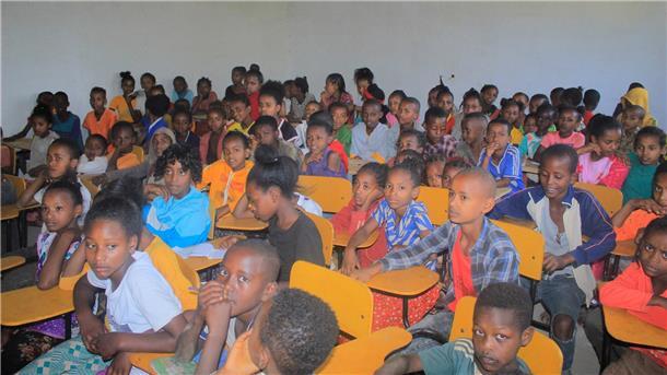 Kinder sitzen in einem Klassenraum zusammen. 