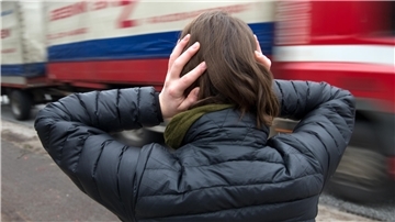  Eine Frau hält sich in Hamburg vor einem nahenden Lastwagen die Ohren zu. 