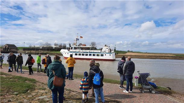 Touristen schauen auf ein Ausflugsschiff in Fedderwardersiel