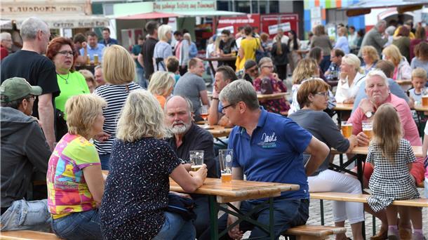 Menschen sitzen an Bierbänken.