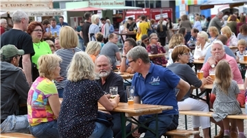 Menschen sitzen an Bierbänken.