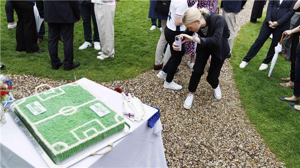 Wesermarsch: Darum warnt das Veterinäramt vor Torten-Bestellungen im Internet Eine junge Frau fotografiert bei einer Feier eine Torte in Form eines Fußballfeldes.