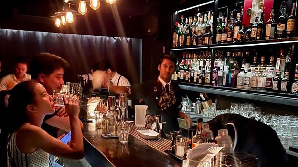 Gäste sitzen am Tresen einer Bar in Bangkok.