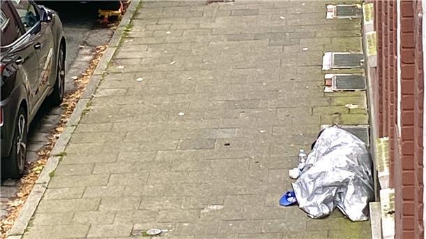 Obdachloser liegt unter einer Alu-Schutzdecke auf der Straße