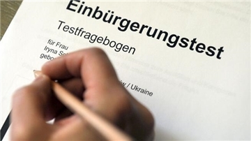 Eine Hand mit einem Bleistift auf dem Testfragebogen Einbürgerungstest. 
