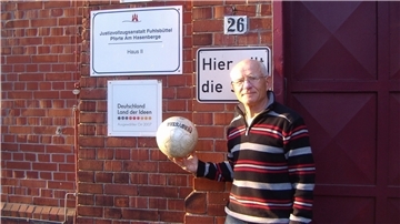 Gerhard Mewes aus Klein Meckelsen steht mit einem Fußball in der Hand vor einer Pforte der Haftanstalt Hamburg-Fuhlsbüttel, im Volksmund „Santa Fu“ genannt. Über seine Zeit als Fußballtrainer im Knast hat der 77-Jährige bereits zwei Bücher verfasst.