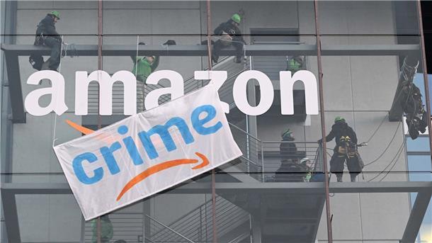 Internationale Anti-Amazon-Kundgebungen am „Black Friday“ Greenpeace-Aktive hängen während der Rabattaktion Black Friday ein Plakat gegen die Ressourcenverschwendung des Online-Versandhändlers Amazon an dessen Gebäude in München auf.