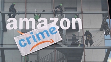 Greenpeace-Aktive hängen während der Rabattaktion Black Friday ein Plakat gegen die Ressourcenverschwendung des Online-Versandhändlers Amazon an dessen Gebäude in München auf.
