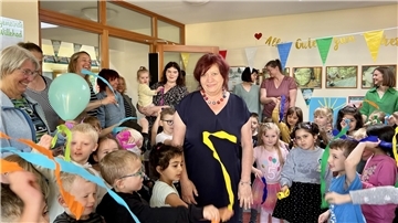 Frau wird von Kindern und Erwachsenen verabschiedet.