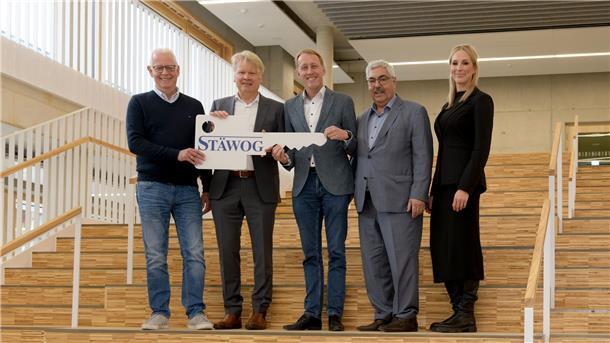 Abschluss eines Mega-Projekts: Neue Grundschule Lehe eröffnet Menschen auf einer Treppe, die einen übergroßen Schlüssel halten.