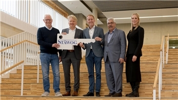 Abschluss eines Mega-Projekts: Neue Grundschule Lehe eröffnet Menschen auf einer Treppe, die einen übergroßen Schlüssel halten.