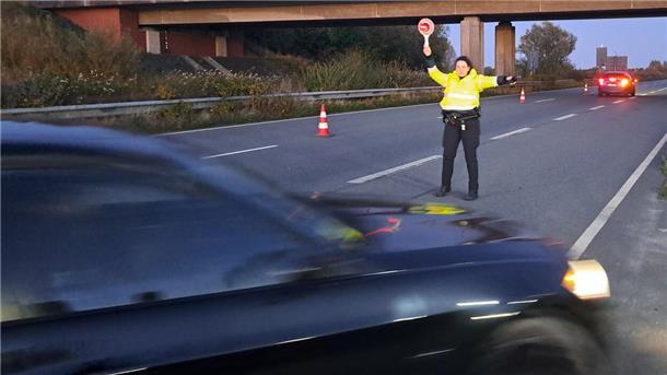 Eine Polizeibeamtin hält einen Autofahrer hinter dem Wesertunnel an. 
