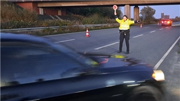 Eine Polizeibeamtin hält einen Autofahrer hinter dem Wesertunnel an. 
