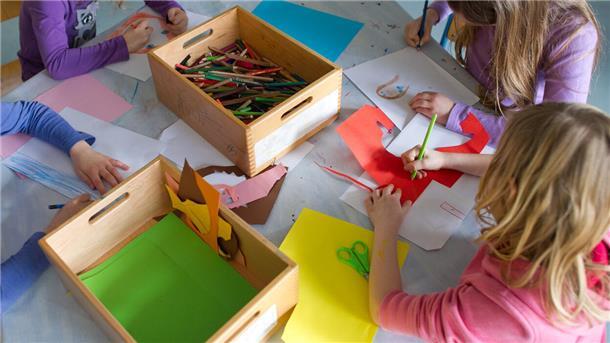 Grundschülerinnen sind in einem Kinderhort mit Bastelarbeiten beschäftigt.