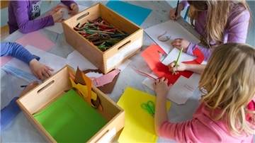 Grundschülerinnen sind in einem Kinderhort mit Bastelarbeiten beschäftigt.