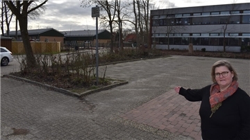 Grundschulleiterin Kerstin Beck zeigt auf diesen befestigten Bereich bei der Grundschule, der sofort und ohne größeren Aufwand offiziell Parkfläche werden könnte - durch entsprechende Markierung und Beschilderung.
