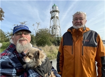 Günter Mehrtens und Jens Wohlkopf (hier mit Hund Napoleon) vom Heimatverein Club Weserstrand sind eng mit Großensiel verbunden - und damit auch mit dem Strandwald. Sie wollen, dass das Areal erhalten bleibt. Im Hintergrund ist das Unterfeuer zu sehen, das Teil der Richtfeuerlinie ist.