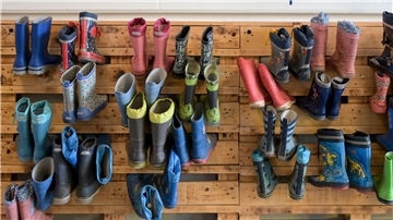 Gummistiefel hängen an der Palettenwand einer Kindertagesstätte in Halle (Saale). In Deutschland fehlen Erzieherinnen und Erzieher.