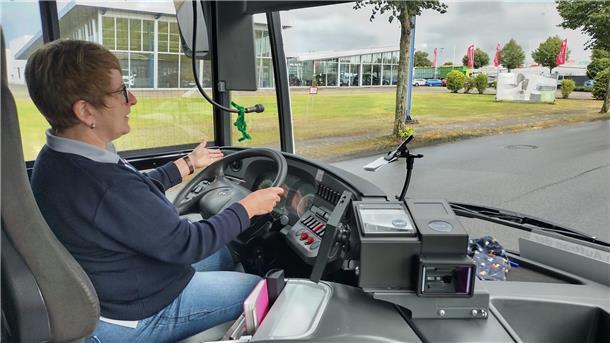 Eine Busfahrerin bei der Fahrt hinter ihrem Lenkrad.