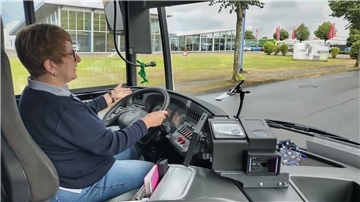 Eine Busfahrerin bei der Fahrt hinter ihrem Lenkrad.