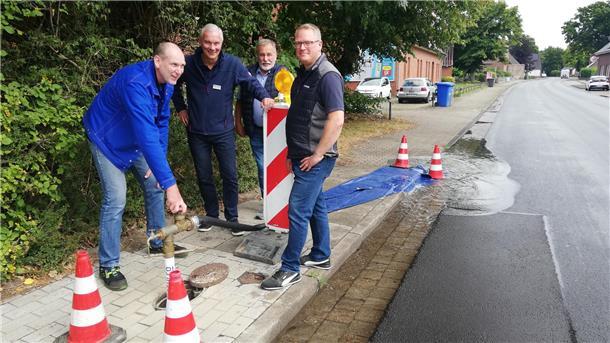 vier Männer an einer Baustellenbarke, ein Mann dreht den Wasserhydranten auf