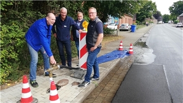 vier Männer an einer Baustellenbarke, ein Mann dreht den Wasserhydranten auf